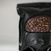 Matte black stand-up pouch with a clear die-cut window revealing roasted coffee beans inside