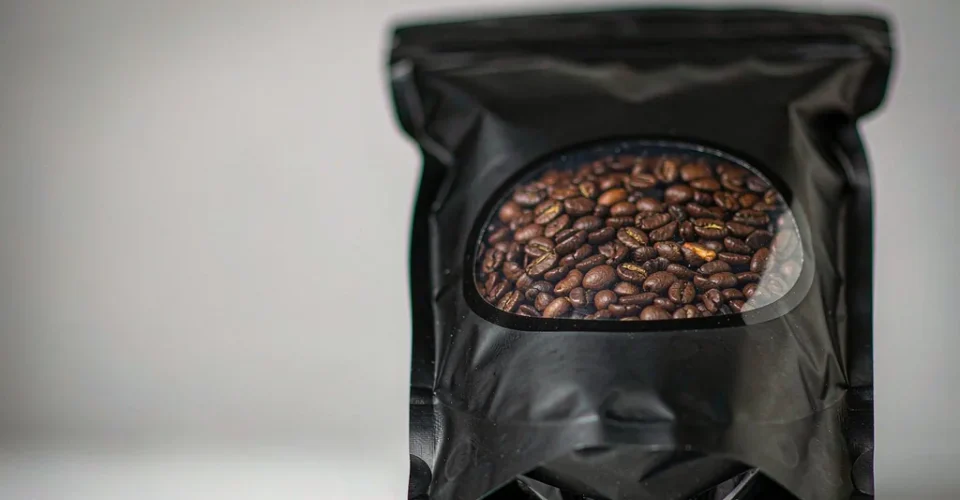 Matte black stand-up pouch with a clear die-cut window revealing roasted coffee beans inside