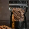 Matte stand-up pouch of beef jerky with resealable zipper on a dark slate surface